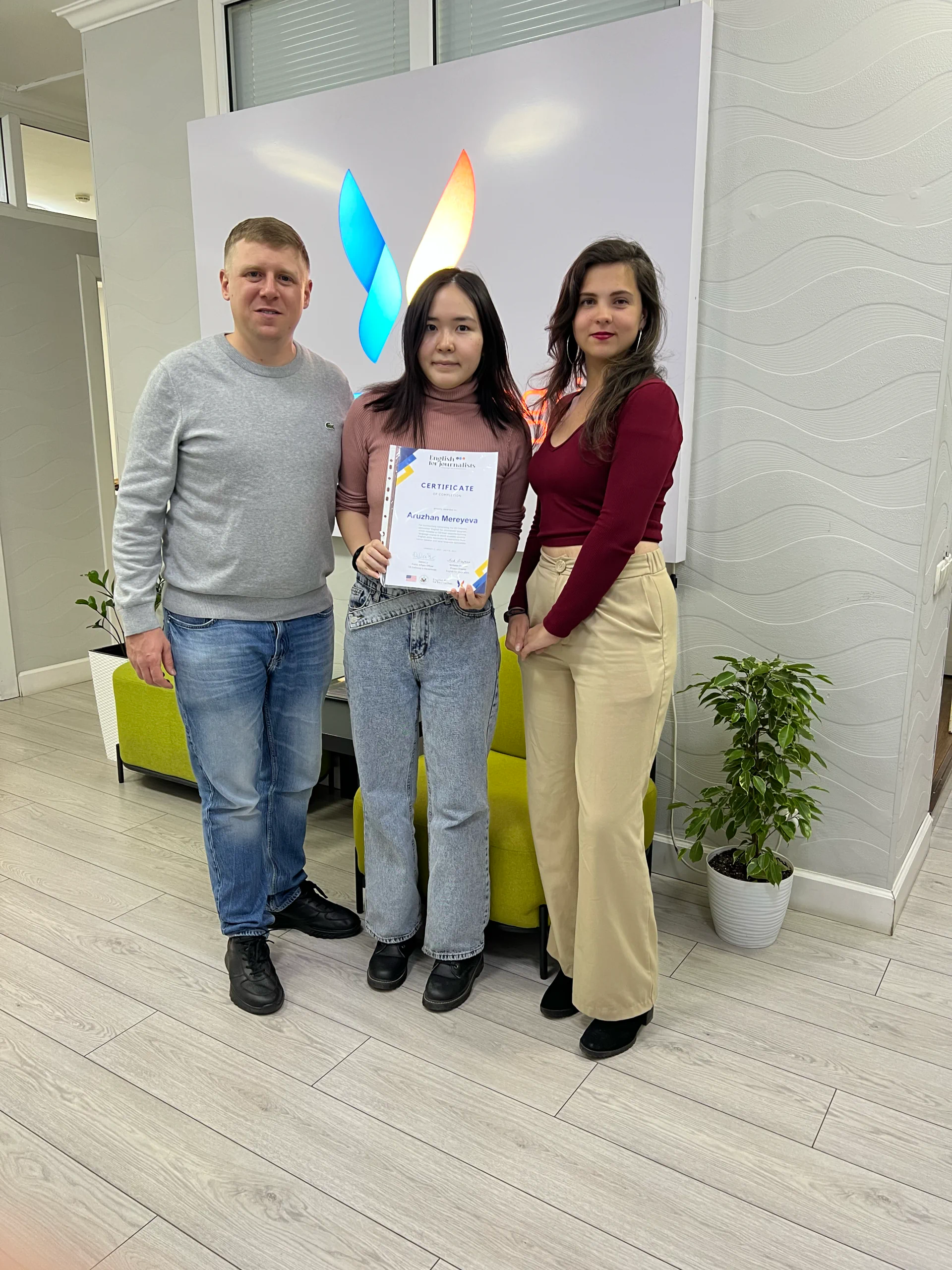 Три человека у логотипа NLE с сертификатом об обучении